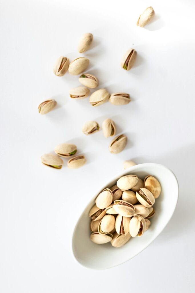 pexels-photo-1799307-1799307 Pistachio nuts in a white bowl on a white background, top view.