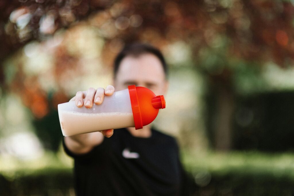pexels-photo-4378601-4378601 Focus on a man holding a plastic protein shake tumbler outdoors with a blurred background.whey nerd