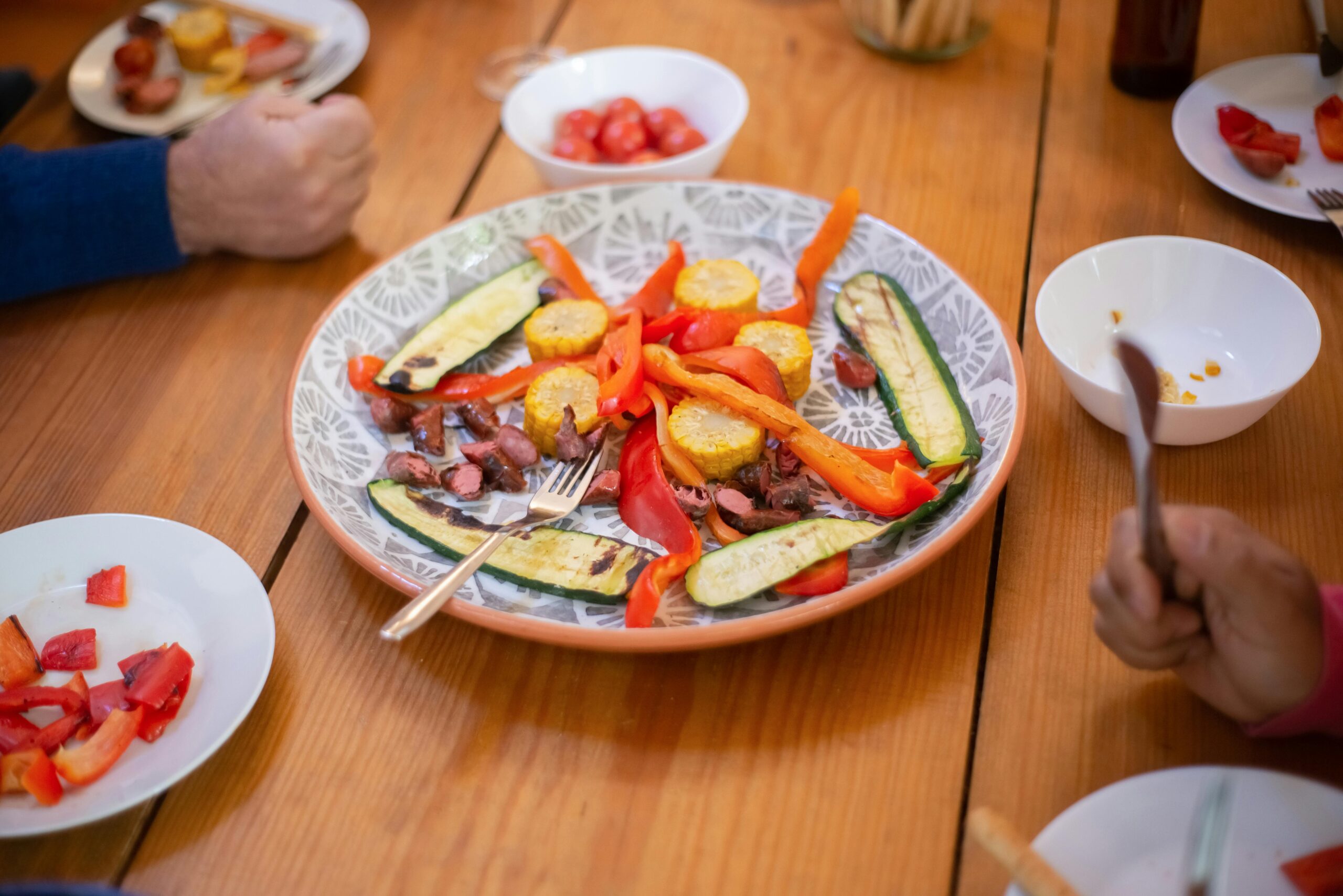 A colorful arrangement of roasted vegetables and meat on a dinner table, perfect for sharing and enjoying with family or friends.