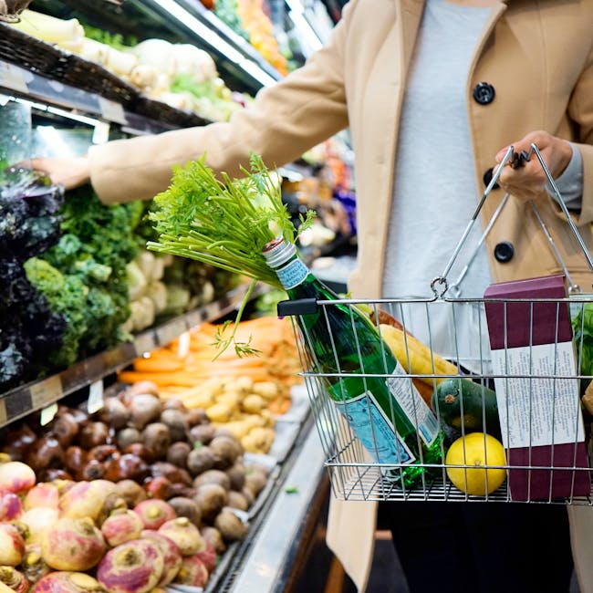 pexels-photo-9070106-9070106 Woman selecting fresh produce in a supermarket with a basket full of groceries.