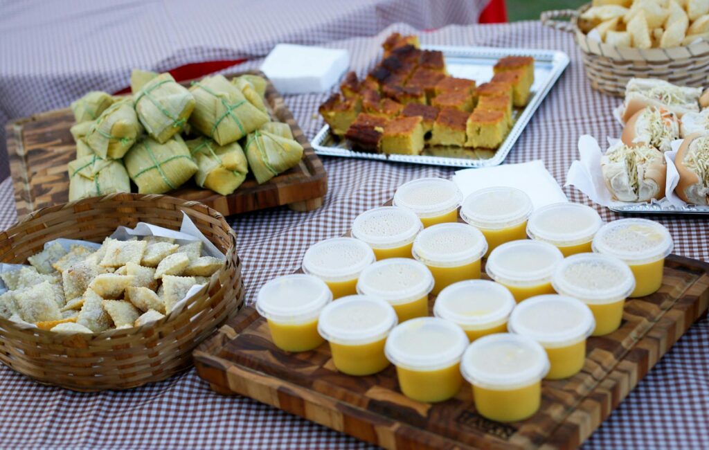 pexels-photo-10949539-10949539 An assortment of traditional dishes including corn cake, tamales, and dessert cups on a checkered table.