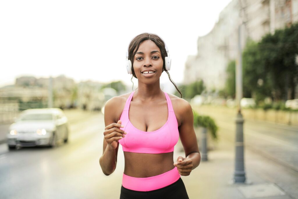 pexels-photo-3807546-3807546 A woman in a pink sports bra jogging outdoors with headphones, embodying a healthy lifestyle.