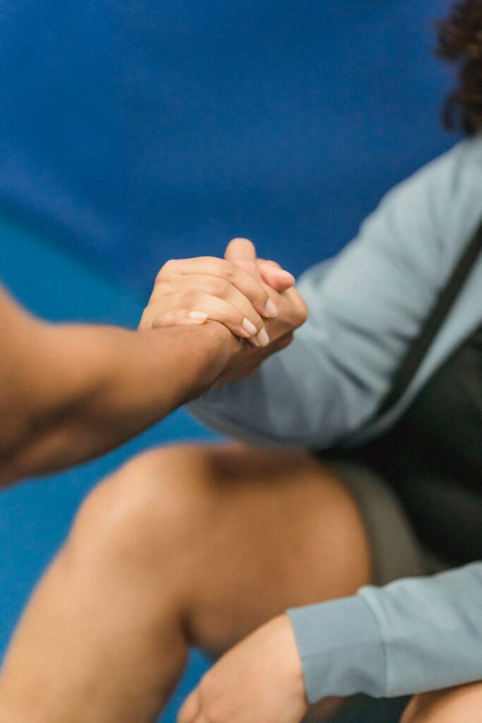 A close-up of a supportive handshake between two women in a gym setting, promoting wellness.