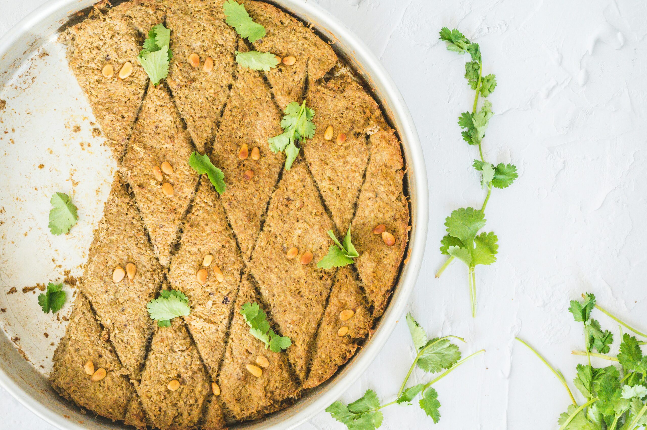 Close-up of traditional kibbeh garnished with fresh herbs in a silver dish, showcasing unique Middle Eastern flavors.