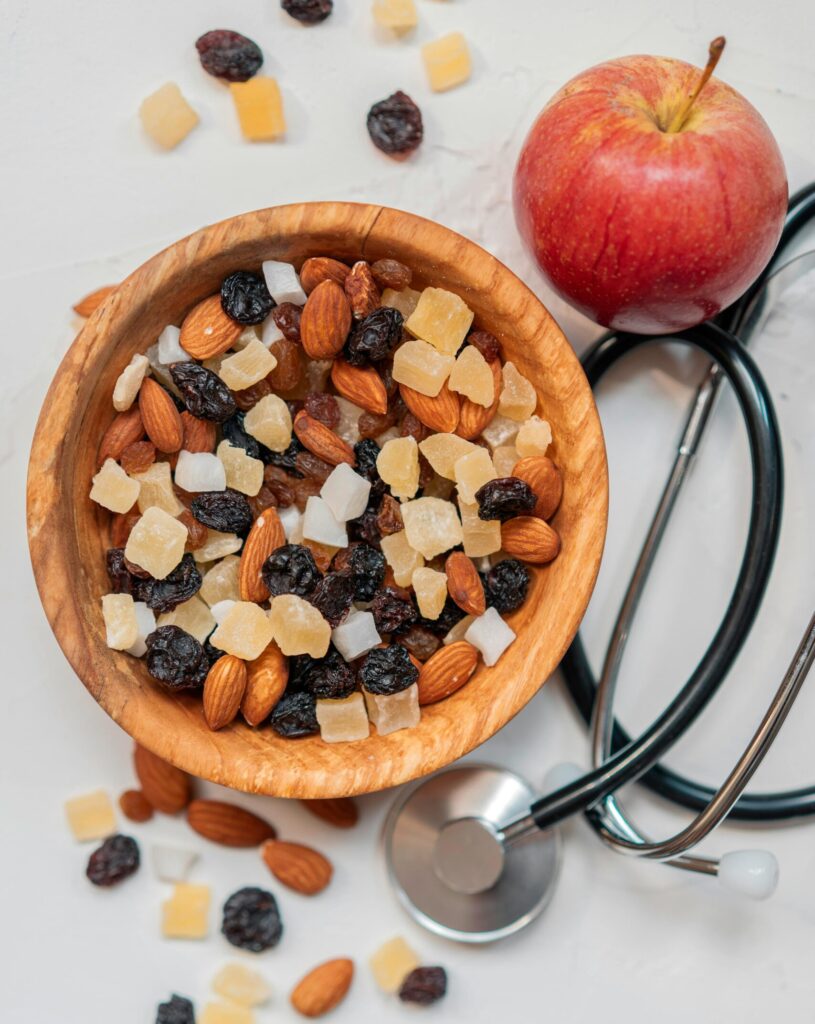 Bolo Funcional de Maçã Top view of a healthy mix of nuts and dried fruits with an apple and stethoscope.