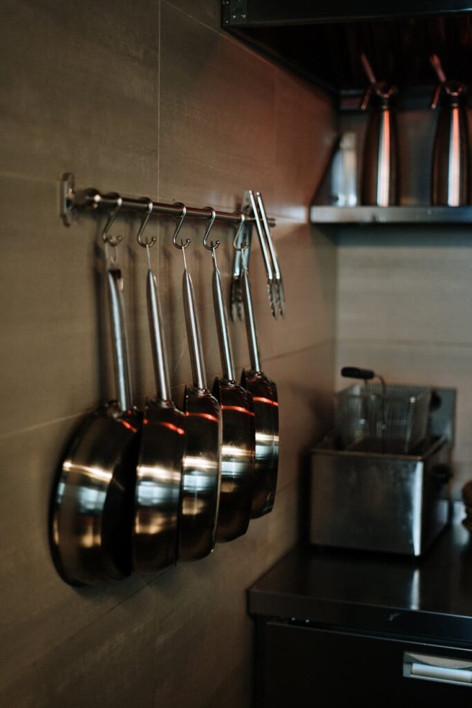 pexels-photo-4252147-4252147 Elegant arrangement of stainless steel pans hanging in a contemporary kitchen setting.