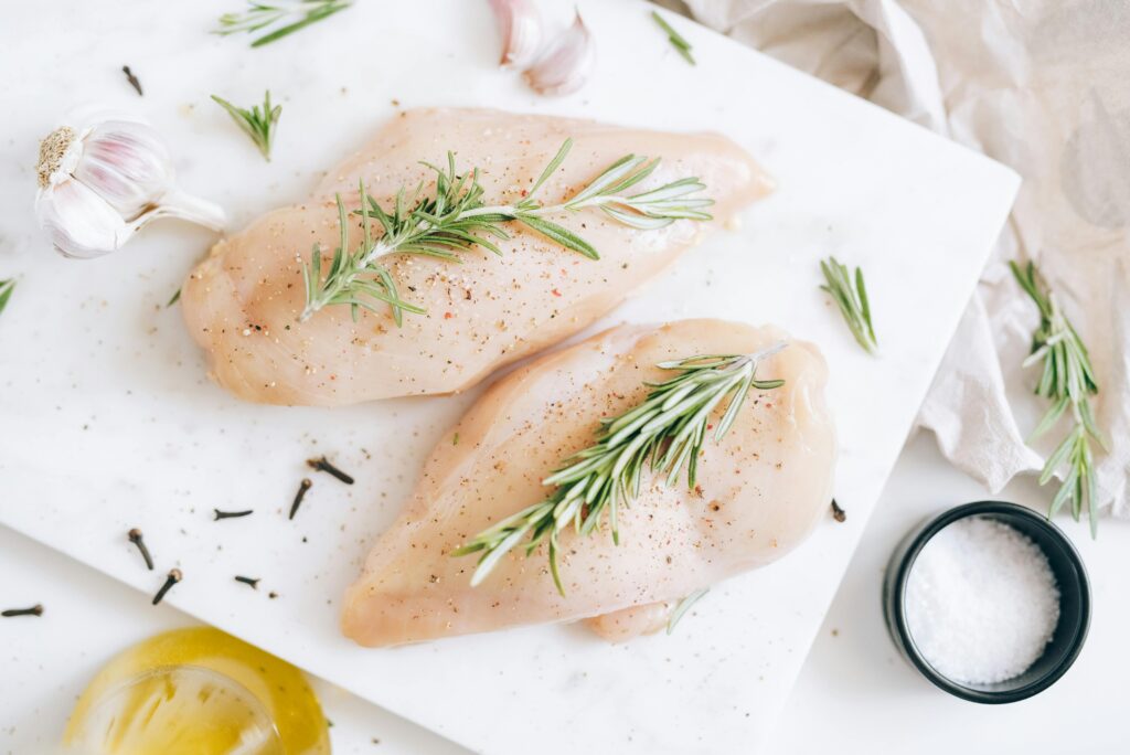 pexels-photo-5769384-5769384 caldo de pinto forte Top-down view of fresh raw chicken breast garnished with rosemary and garlic.
