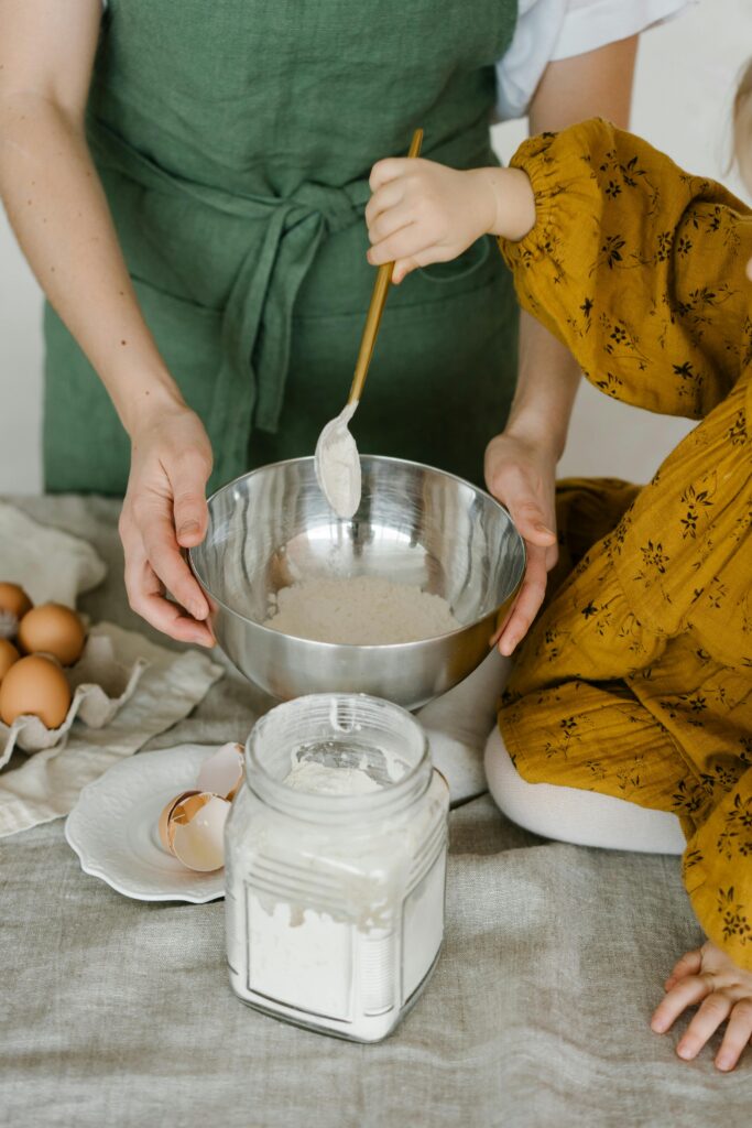 pexels-photo-6957818-6957818 Mother and child mixing dough in a bowl, symbolizing family togetherness and home baking.